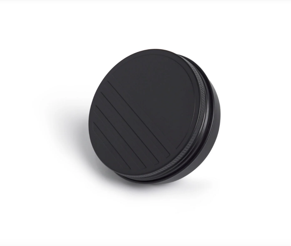 Black circular tin of sunscreen with textured surface on a white background