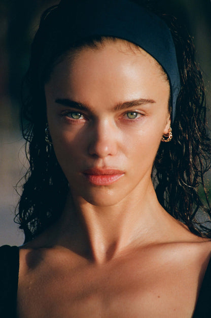 Close-up of a person with a dark headband against a blurred natural background